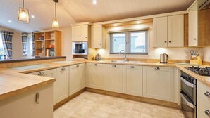 Une cuisine moderne avec des meubles en bois, un four à micro-ondes encastré, un évier en acier inoxydable et une cuisinière à gaz.