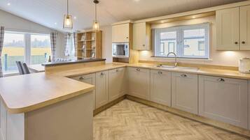 A kitchen with a herringbone floor pattern, a built-in microwave, and a window with blinds.