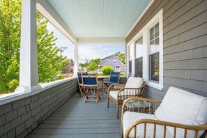 A covered porch with a table and chairs, a view of a house, and a brick wall.