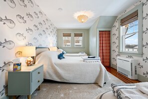Un dormitorio con dos camas, una mesita de noche, una lámpara, un calefactor y una ventana con vistas.