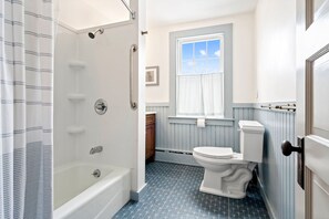 Un baño con bañera, ducha, inodoro y ventana.