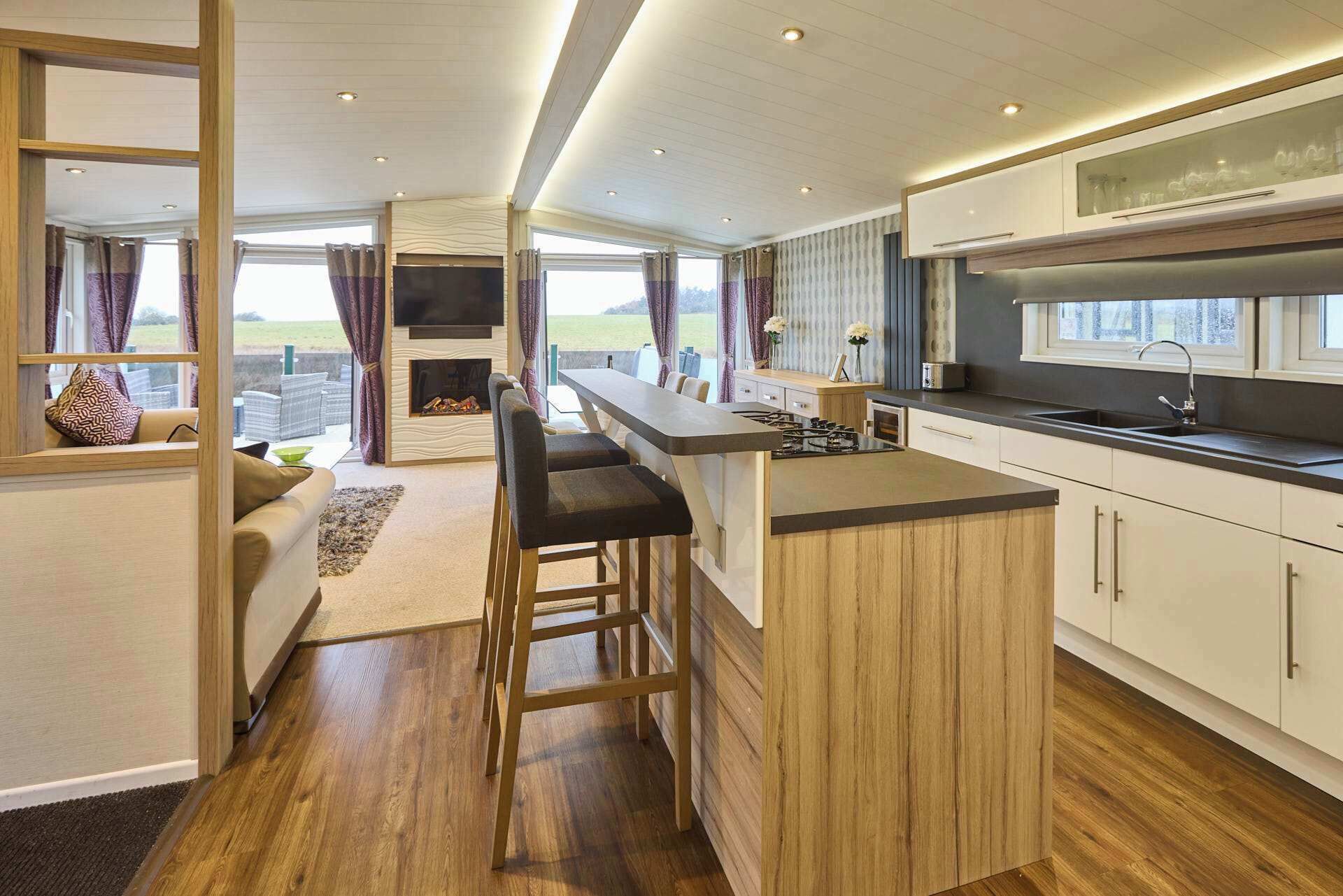 Een moderne keuken met een bar, houten kastjes en uitzicht op de omgeving.