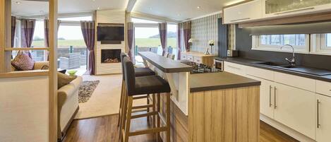 Een moderne keuken met een bar, houten kastjes en uitzicht op de omgeving.