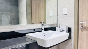 Une salle de bain moderne avec un lavabo blanc, un plan de toilette noir et une porte en bois.