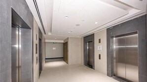 Un área de ascensor moderna, con paredes metálicas y un piso de baldosas impecable.
