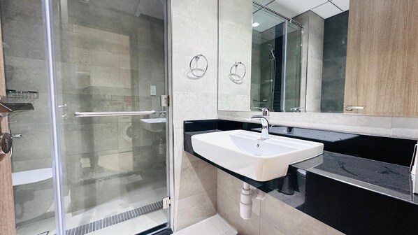 Une salle de bain moderne avec une douche à parois de verre, un lavabo blanc et un grand miroir.
