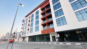 Un hotel moderno con fachada blanca, varios balcones y grandes ventanales.