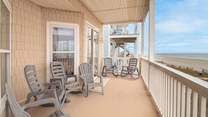 A covered porch with several chairs and a view of the beach. - Oceanfront 30+ day rental! (Folly Beach)