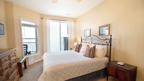 A bedroom with a large bed, a dresser, a nightstand, and a window with a view. - Oceanfront 30+ day rental! (Folly Beach)