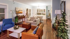 A living room with a blue armchair, a beige sofa, and a wooden coffee table. There is a Christmas tree and a painting on the wall. - Pleasant Stay in Pella (Pella)
