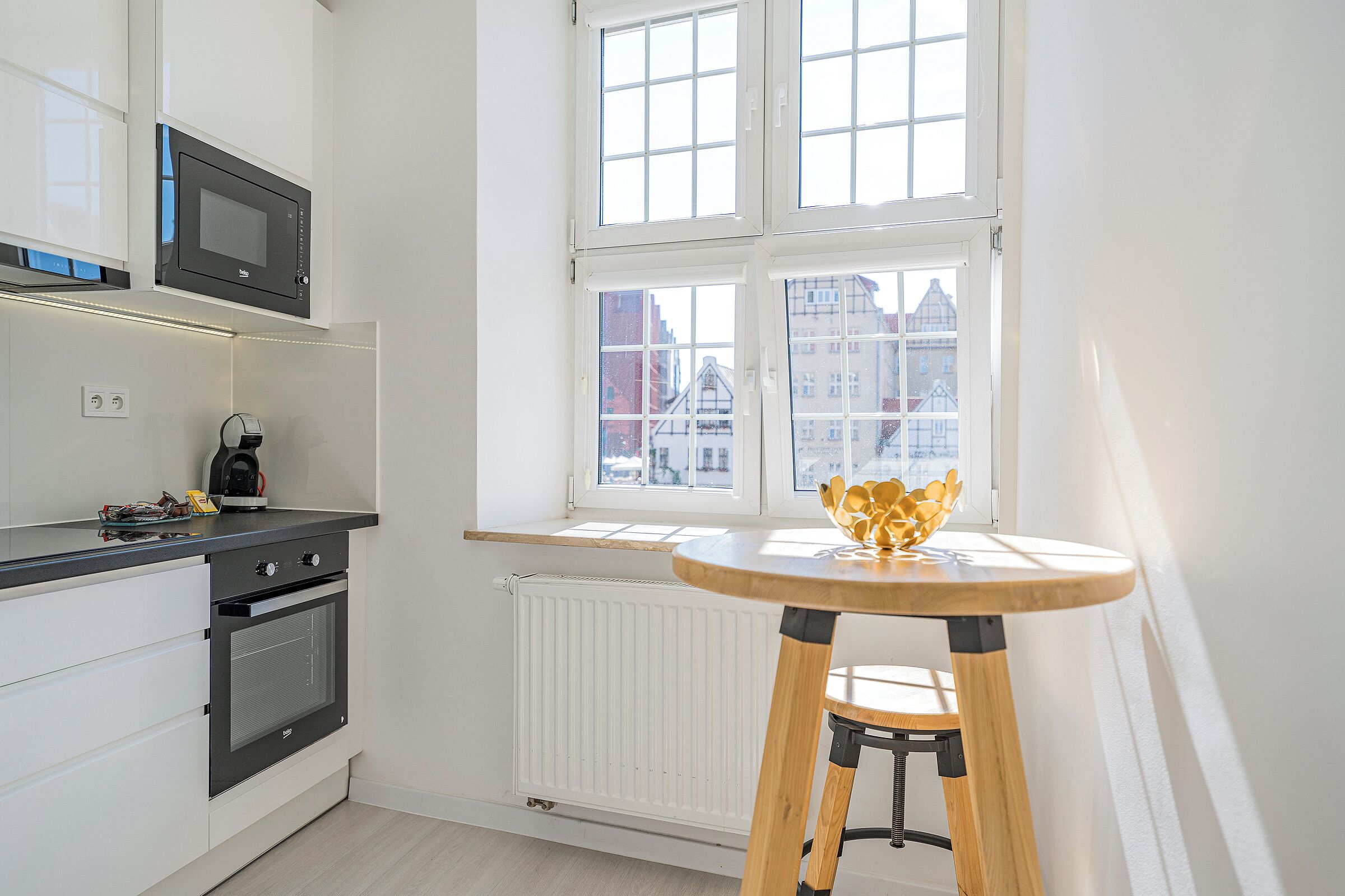 Uma cozinha moderna com micro-ondas, forno embutido e janela com vista para a cidade.