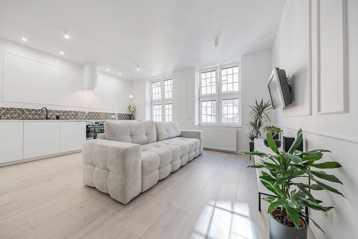 A modern kitchen with white cabinetry, a built-in oven, and a large window.
