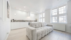 Una cocina moderna con armarios blancos, salpicadero de azulejos grises y horno empotrado.