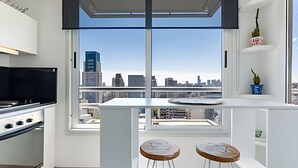 Une cuisine moderne avec vue sur la ville, une grande fenêtre et deux tabourets.