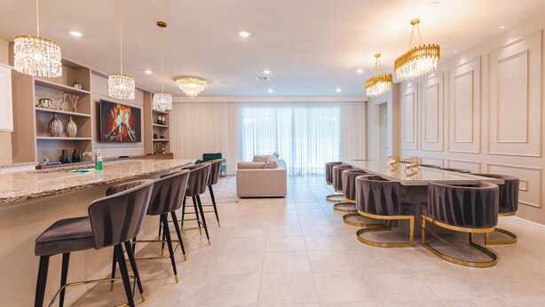 A modern kitchen with a bar area, a dining table with chairs, and a sofa.