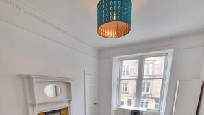 A bedroom with a bed, a fireplace, a desk, and a window with a view of buildings. - Traditional Victorian Edinburgh Flat Central Location, Bright and Airy (Edinburgh)