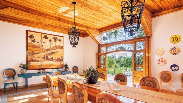 A dining area with a wooden table, chairs, and hanging light fixtures. - Casa de Campo el Edén (Armenia)