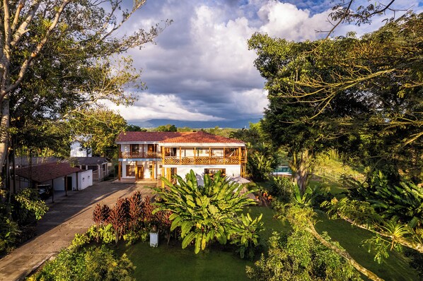 A two-story house with a balcony, surrounded by lush greenery and a clear sky. - Casa de Campo el Edén (Armenia)
