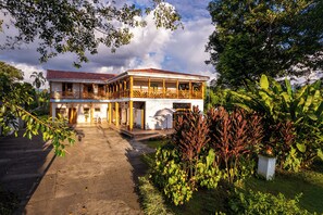 A two-story building with a balcony, surrounded by lush greenery and a paved driveway. - Casa de Campo el Edén (Armenia)