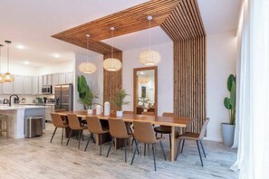 Una cocina moderna con armarios blancos, electrodomésticos de acero inoxidable y una mesa de comedor de madera con sillas.