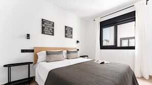 Una habitación de hotel moderna con una cama grande, un cabecero de madera y vistas a la ciudad a través de un ventanal.
