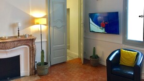 Ein Wohnzimmer mit Kamin, einem an der Wand befestigten Fernseher, einer Tür zu einem anderen Raum und einem Blumentopf.