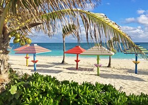 Una playa con sombrillas a rayas de colores y palmeras.