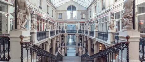 A multi-level shopping arcade with ornate railings and statues.