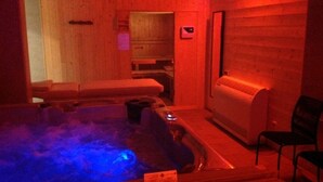 Una habitación de madera con un jacuzzi, una camilla de masaje y un sillón de masajes.