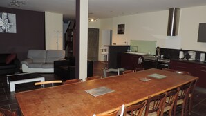 Un espacio habitable amplio con una mesa de comedor, sillas, un sofá y una cocina con estufa y fregadero.