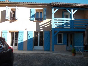 Ein zweistöckiges Gebäude mit blauen Fensterläden und einem Balkon.