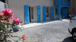 A building with blue shutters, a gravel driveway, and a parked car.