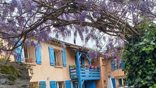 A house with a balcony, a car parked in front, and a bicycle.