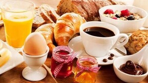 Une table dressée pour le petit-déjeuner avec des croissants, des œufs, des fruits et des boissons.