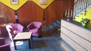 Un hall d’entrée avec un comptoir de réception, un escalier et un espace détente.