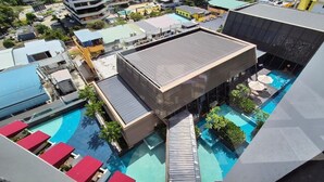 A modern hotel with multiple swimming pools, a rooftop terrace, and a view of surrounding buildings. - Sutra Bay (Kota Kinabalu)