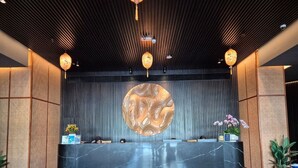 A reception area with a marble counter, a large circular wall art, and traditional decor. - Sutra Bay (Kota Kinabalu)