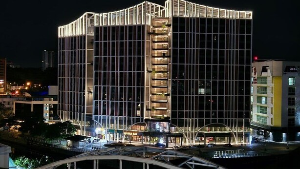 A modern building with a grid-like facade, multiple balconies, and a prominent entrance area. - Sutra Bay (Kota Kinabalu)