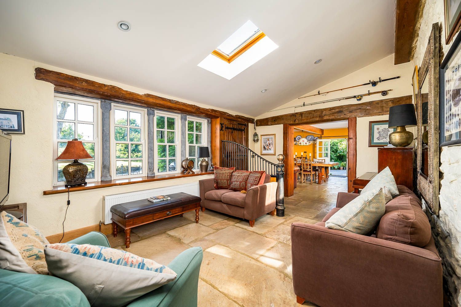 A spacious living room with a high ceiling, large windows, and a staircase leading to an upper level.