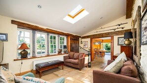 Una sala de estar acogedora con chimenea, un ventanal grande y una escalera que sube a un nivel superior.