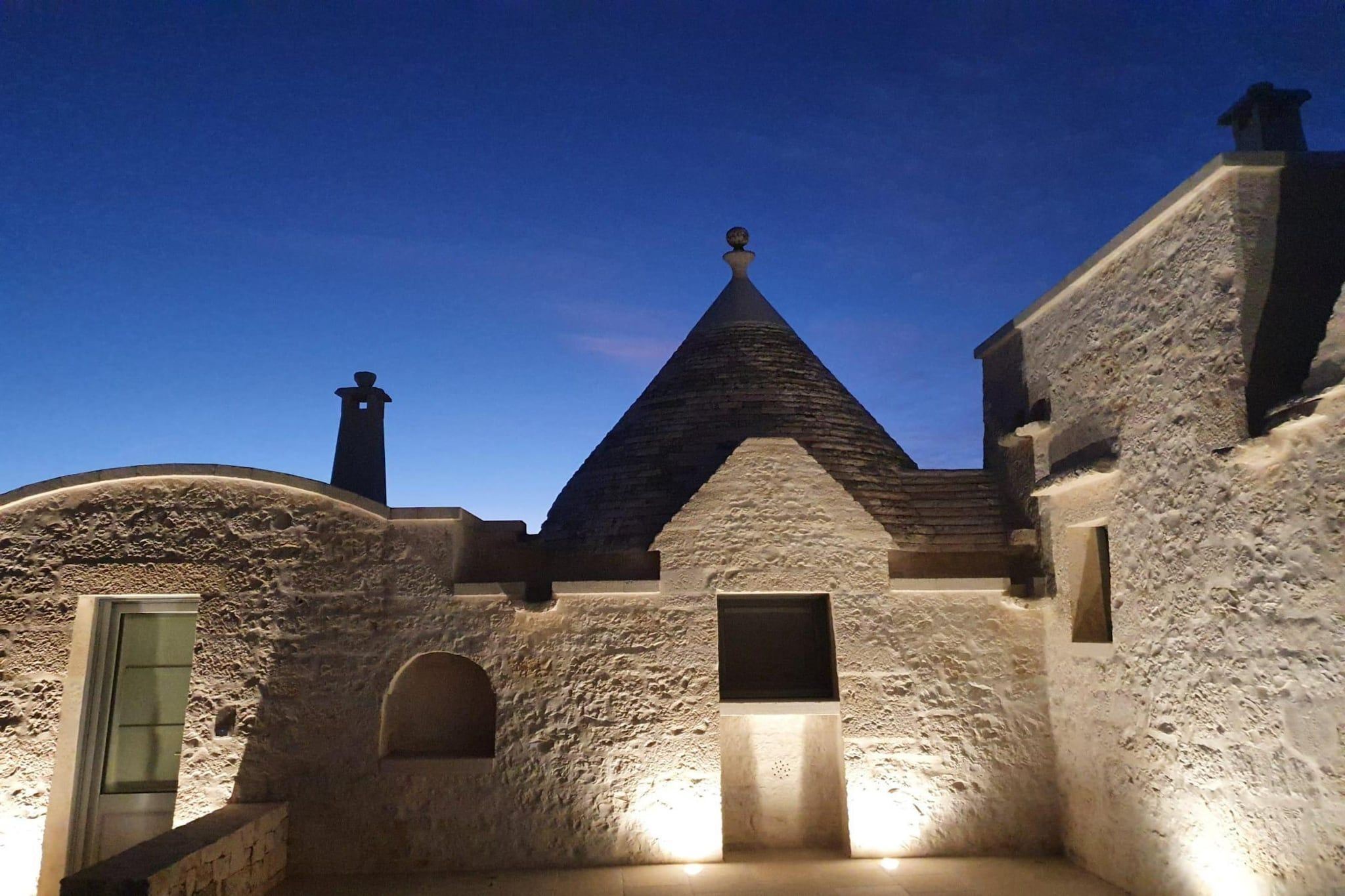 A building with a stone facade, a pointed roof, and a door.