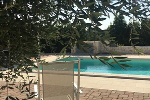 A pool area with a chair and a stone wall in the background.