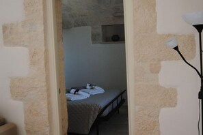 A narrow doorway leading to a room with a bed and a small window.