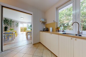 A modern kitchen with a window, a sink, and a dining area with chairs and a table.