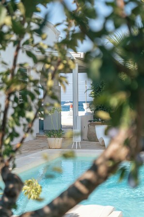 A pool area with a view of the sea, surrounded by potted plants and a white chair. - Nialè - Luxury & Relaxation by the Sea (Polignano a Mare)