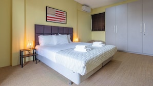 A neatly made bed with white linens, a headboard, and a bedside table with a lamp.