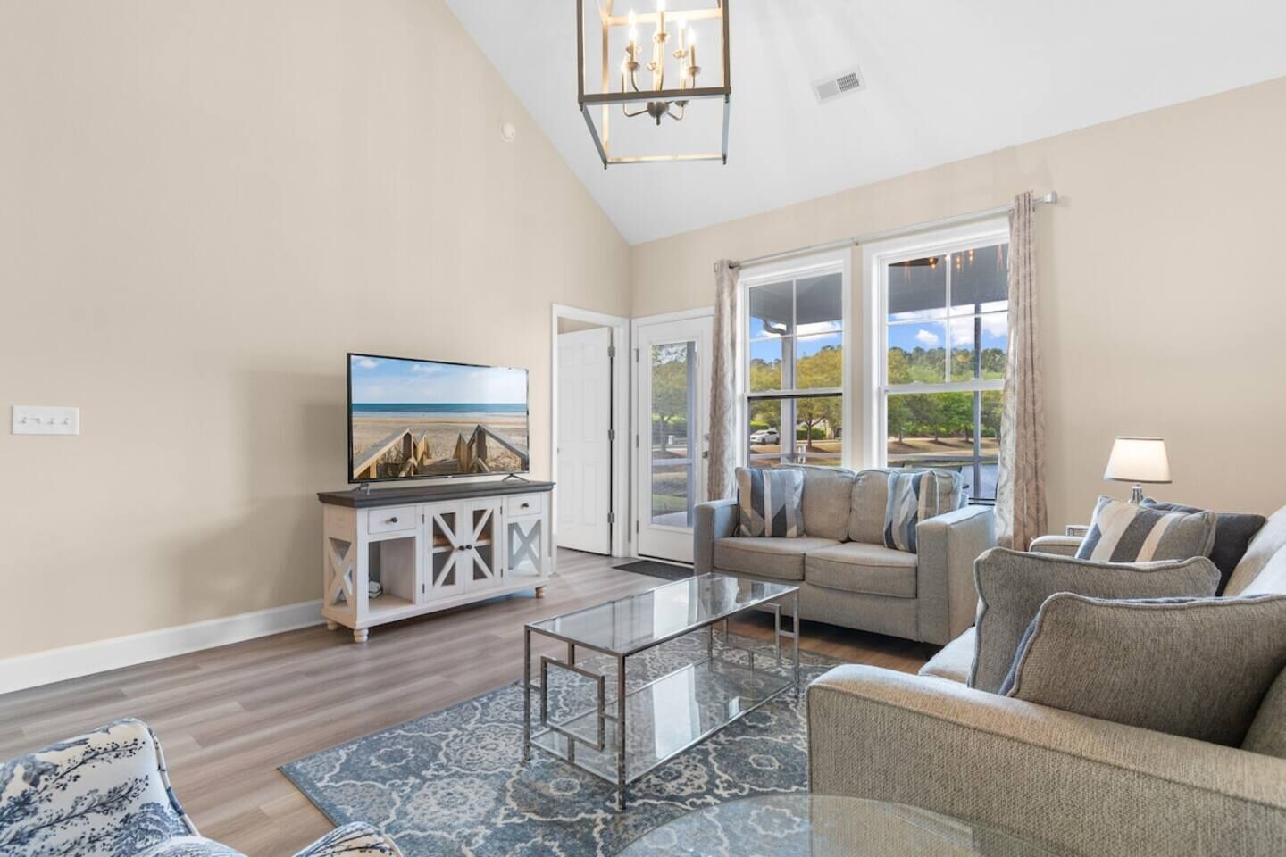 A living room with a television, a sofa, a coffee table, and a view of the outdoors.