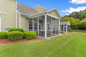 A house with a covered porch, a lawn, and a small garden with bushes. - Cozy Barefoot Resort Condo - Pool & Golf (North Myrtle Beach)
