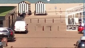 A parking area with a beach view, a kiosk, and a few people walking. - Kabine7 (Koksijde)