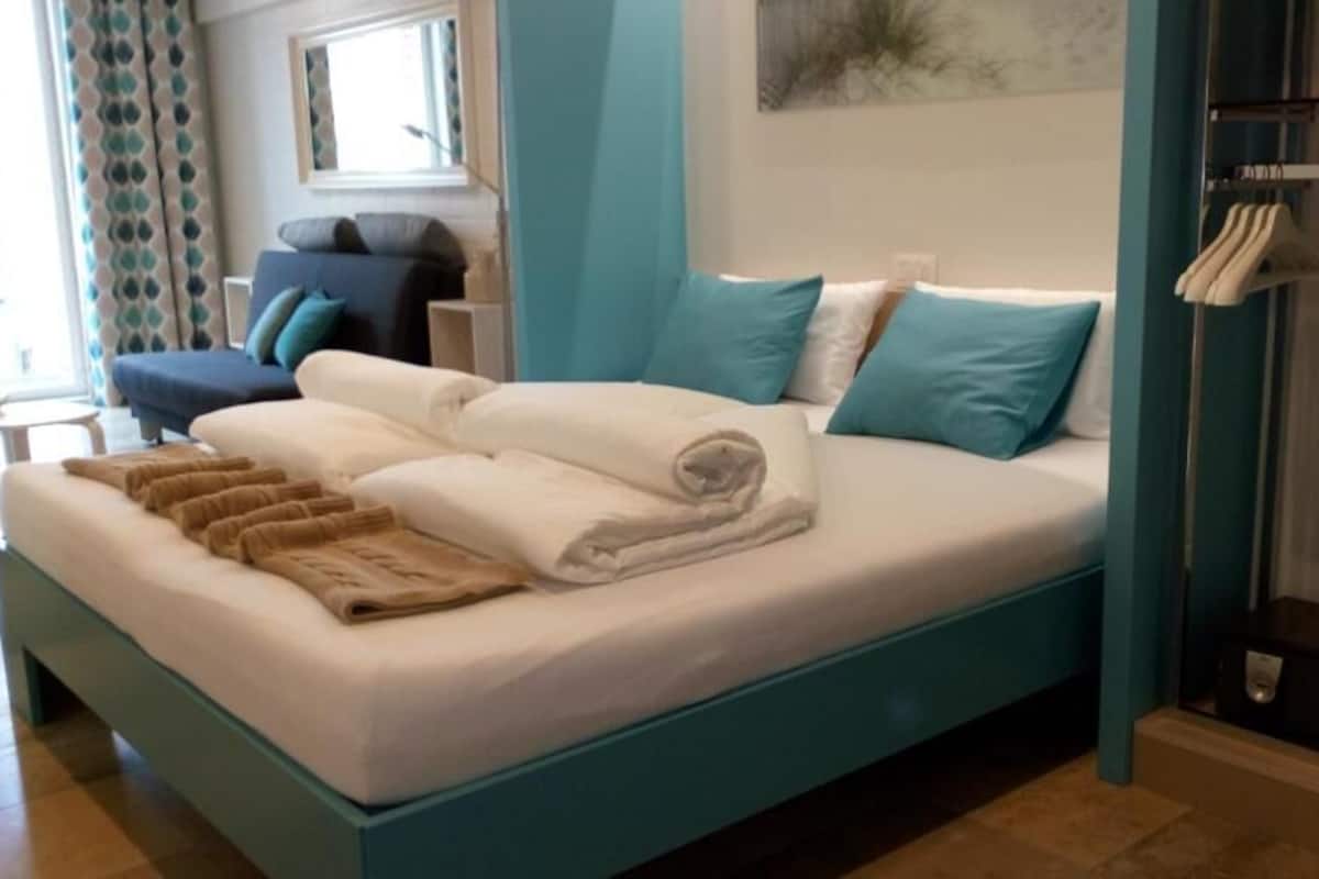 A bed with white and blue bedding, a blue headboard, and a side table.
